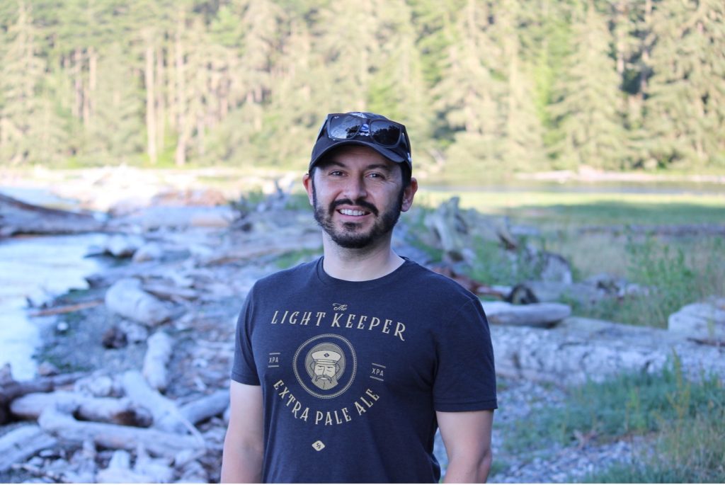 photo of seminar speaker Joseph Heras standing in a field with trees in the background.